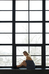 slender girl sits on the windowsill of a large stained-glass window