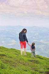 Naklejka premium Mom and baby stand and watch the sunset in the mountains