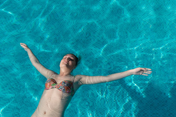 Pretty young girl in swimsuit is swimming in pool