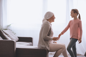 Obraz premium side view of kid and sick grandmother in kerchief looking at each other at home
