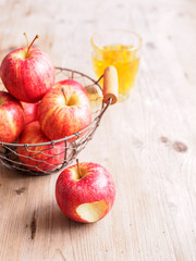 Rote Äpfel in einem Drahtkorb, ein Glas Apfelsaft 