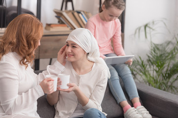 women drinking tea and child using digital tablet, cancer concept