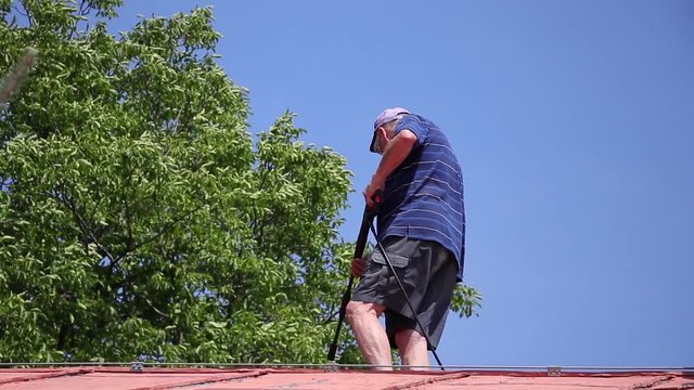 Dangerous work on a rooftop, accident during cleaning a roof by high pressure washer. 