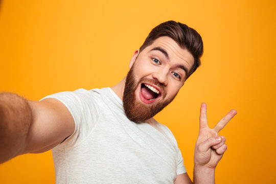 Portrait of a cheerful bearded man showing peace gesture