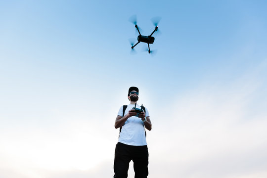 Man flying a drone copter by operating it