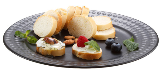 Sandwiches with mascarpone cream cheese, fresh berries and nuts on a black plate. Isolated on a white background.