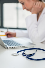 Side view close-up of the hands of a female physician typing on a wireless laptop at desk in the office of a modern hospital