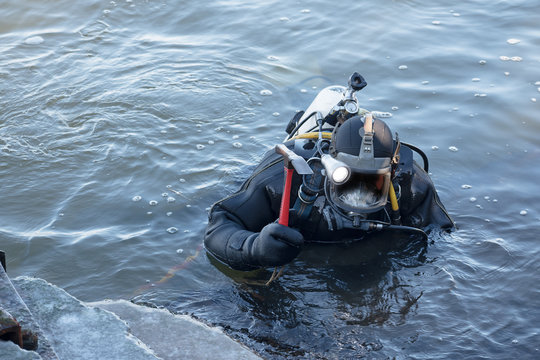 industrial diver with scuba gear and hammer working in the water at the shore reinforcement, copy space