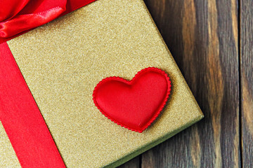 gift box with red bow and heart on wooden background. gift with love