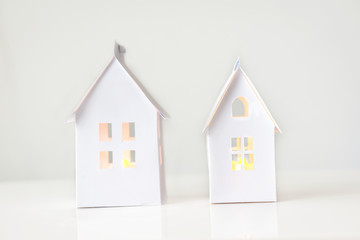 Close-up of hand-made houses made of cardboard for decoration with windows and light, on a white background. Concept architecture and decoration.