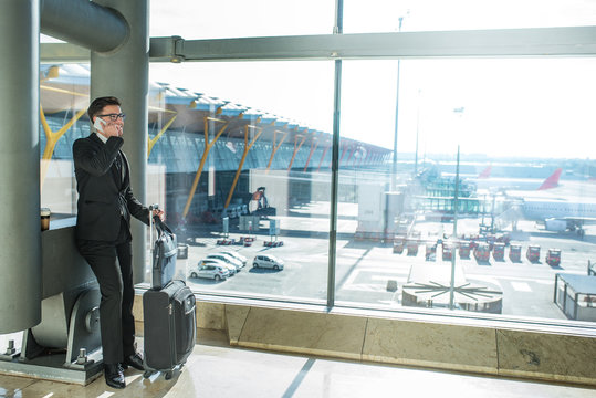 handsome businessman standing waiting for his flight at the airport close to the terminal window