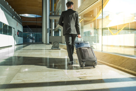 businessman back and legs walking with luggage at the airport