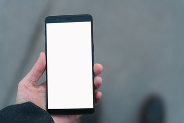 man hand holding smarphone with white screen outdoors in town