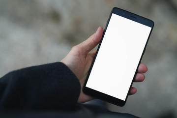 man hand holding smarphone with white screen outdoors in town