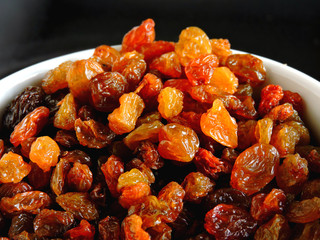 Golden raisins in a white bowl. Close up.