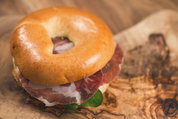 bagel with coppa and cream cheese on wood boar