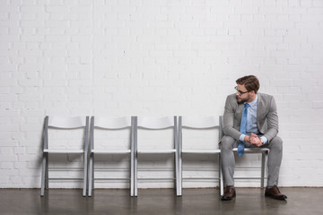 caucasian businessman looking at empty chairs while waiting for job interview
