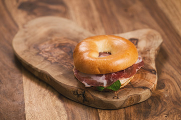 bagel with coppa and cream cheese on wood boar