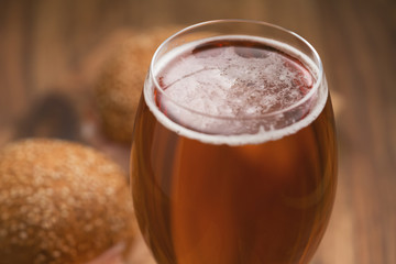 glass of amber beer agains sanwiches with ham