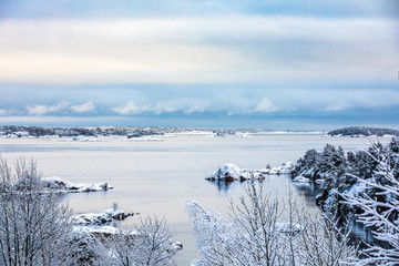Fototapeta na wymiar Beautiful winter day at Odderoya in Kristiansand, Norway. Trees covered in snow. The ocean and archipelago in the background.