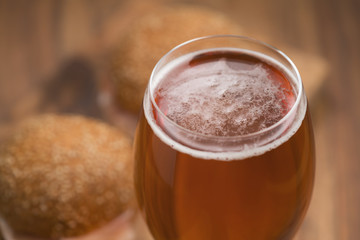 glass of amber beer agains sanwiches with ham