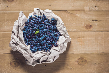 Fresh honeysuckle blue berry fruits with leaf on a wooden background