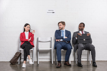multiethnic business people looking at each other while waiting for job interview