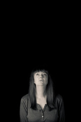 Obraz premium Minimal portrait of mid aged woman looking up skywards. Vertical low key monotone with lots of copy space.