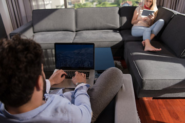 couple relaxing at  home using tablet and laptop computers
