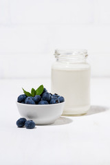 fresh blueberries and a bottle of milk on white table