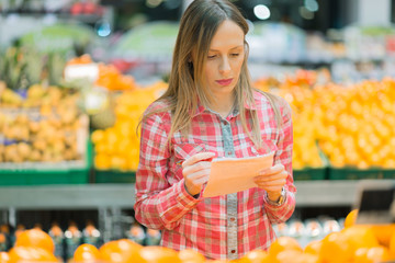 Woman looking at her shopping list in the fruit store