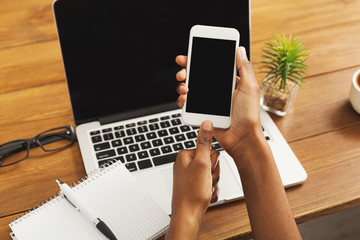 Black woman using smartphone at workplace, closeup