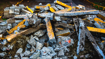 A pile of construction debris made of concrete, bolts and stones with peeling yellow paint