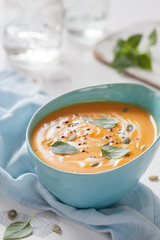 Roasted pumpkin and carrot soup with cream and pumpkin seeds