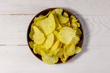 Plate of potato chips on white wooden table