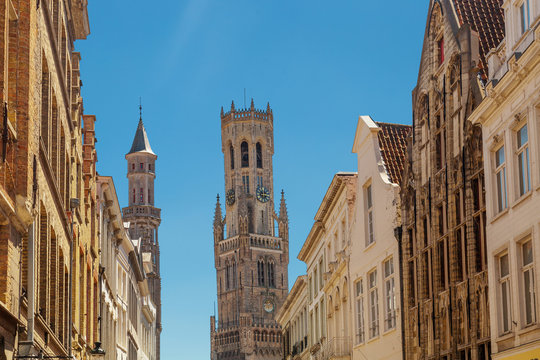 Red brick houses and Belfry tower. Typical street with medieval Flemish architecture of Bruges, Belgium.