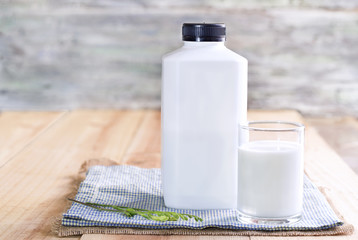 a glass of milk and plastic bottle of milk on the wood table.