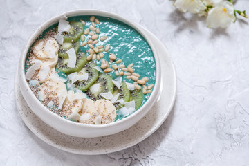 Obraz na płótnie Canvas Breakfast spirulina coconut smoothie bowl topped with coconut flakes and berries