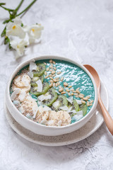 Breakfast spirulina coconut smoothie bowl topped with coconut flakes and berries