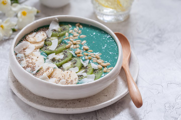 Breakfast spirulina coconut smoothie bowl topped with coconut flakes and berries