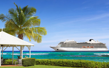 Tropical white gazebo on a sea shore with palm tree and cruise ship in background