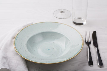 Empty plate, fork, knife and wine glasses on white table