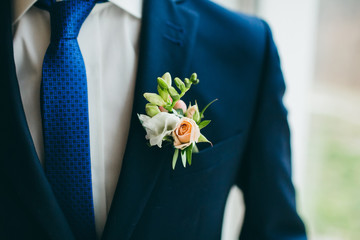 Close up image of beautiful boutonniere on the groom's jacket. Soft focus on boutonniere. Artwork - obrazy, fototapety, plakaty