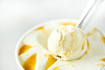 Vanilla ice cream scoop background. Summer food concept, copy space, top view. Scooped texture. Scooping out yellow mango ice-cream.
