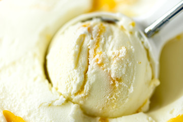 Vanilla ice cream scoop background. Summer food concept, copy space, top view. Scooped texture. Scooping out yellow mango ice-cream.