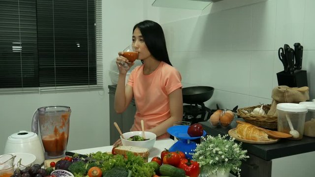 4k of young woman with smoothies in glass at kitchen room