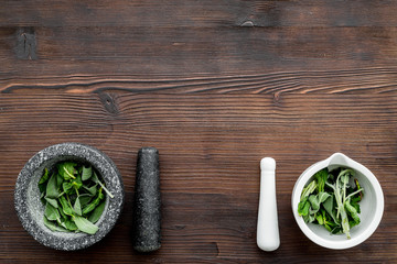 Harvest medicinal herbs. Greens in mortar bowl on dark wooden background top view copy space