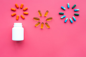 Medicine. Color capsules near pill bottle on pink background top view copy space. fireworks of flower shape