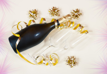 Bottle of champagne and two glasses on horizontal position, gold ribbon and gold gift bows. Beige background