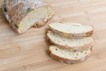 Mouldy unhealthy bread cut in slices with a knife.